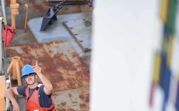 Seaman Joseph Griffin points to the Coast Guard Tahoma's bridge as the vessel sets sail for UNITAS 2018