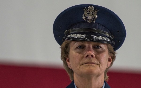 A U.S. Air Force officer named Miller, identifiable by the name tag, is wearing a formal dress blue uniform with general officer rank insignia (stars visible on shoulder boards). The officer is adorned with numerous service ribbons, a pilot's wings badge, and other military decorations. The image appears to be taken at an official military ceremony, with a red and white background visible.