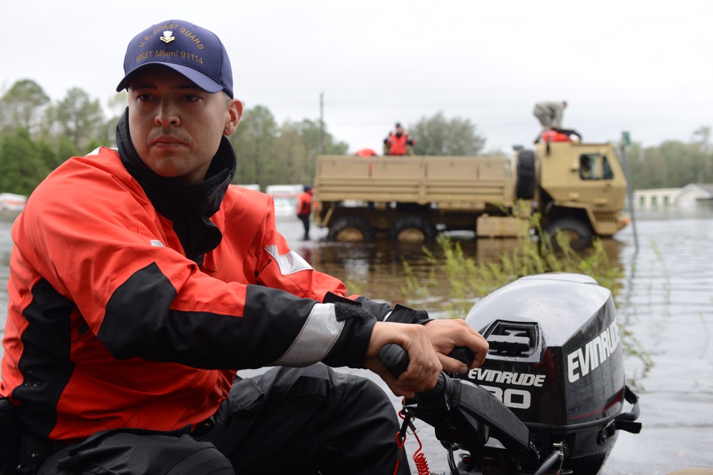 Coast Guard crew member navigates flood waters during search and rescue operations