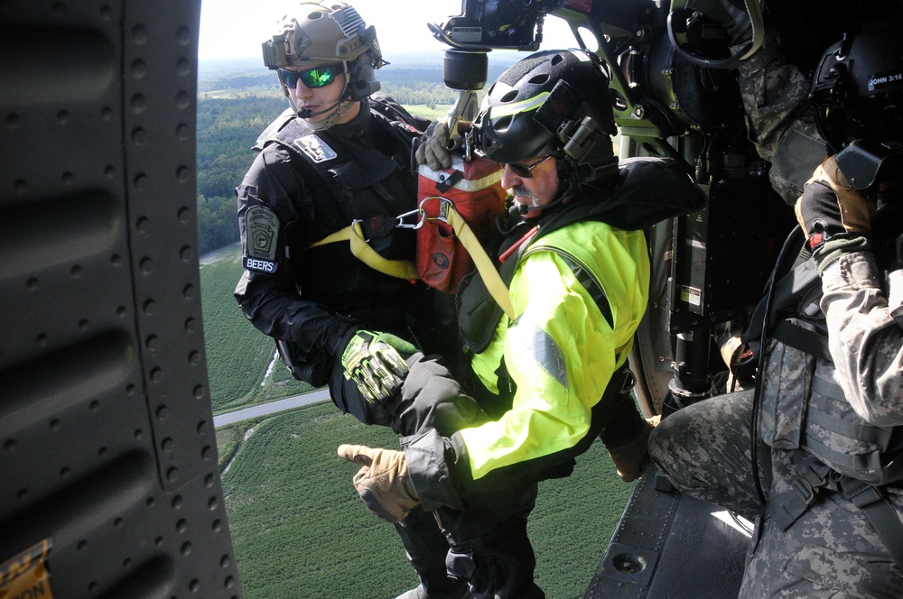 Soldiers prepare to conduct an aerial rescue on a hoist from a UH-60 Black Hawk helicopter.