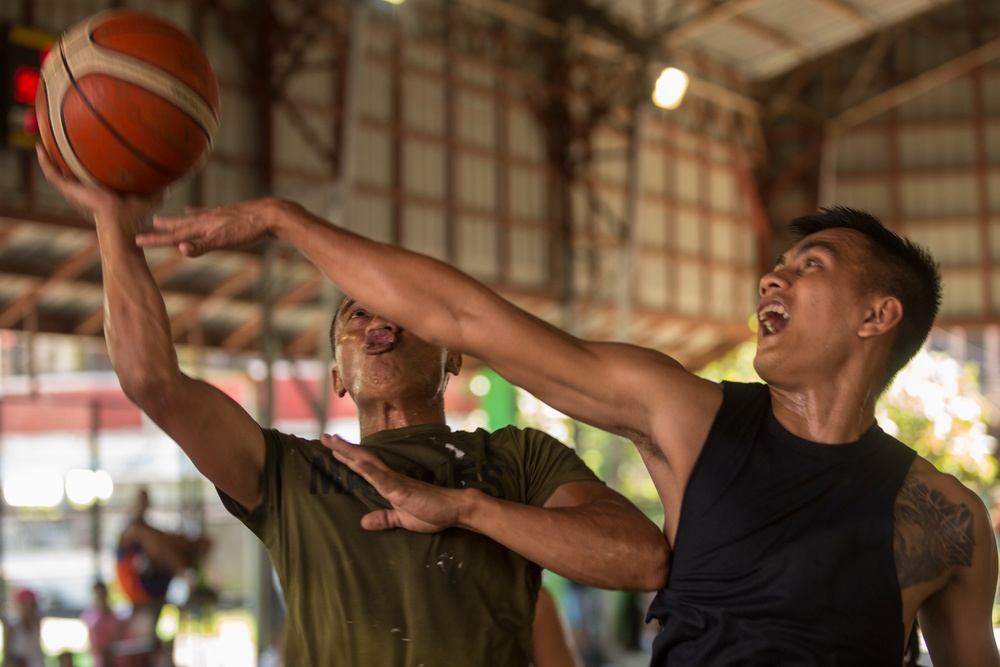 Service members and Barangay Pablicion Uno play basketball during KAMANDAG 2