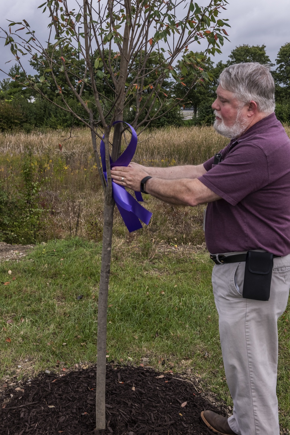 Associate ties ribbon at Hope Garden supporting Domestic Violence Awareness Month