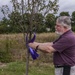 Associate ties ribbon at Hope Garden supporting Domestic Violence Awareness Month
