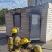 Firefighters with the 128th Air Refeuling Wing spray water at a structural trainer to extinguish a fire during their annual training at Volk Field Combat Readiness Training Center