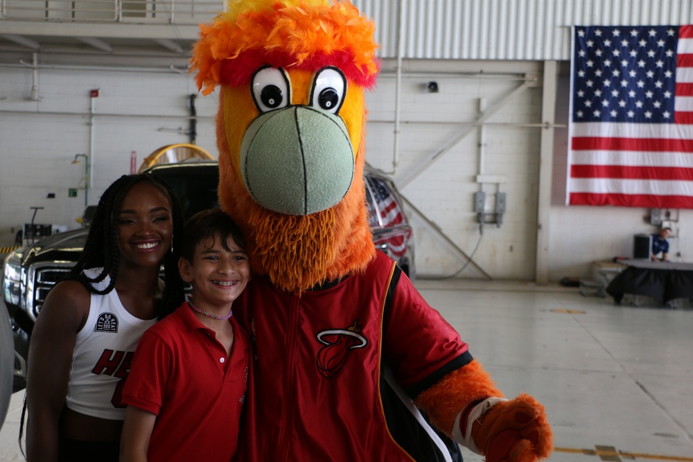 Student takes a picture with the Miami Heat Mascot Burnie and one of the Miami Heat's cheerleader during the open house hosted at Air Station Miami