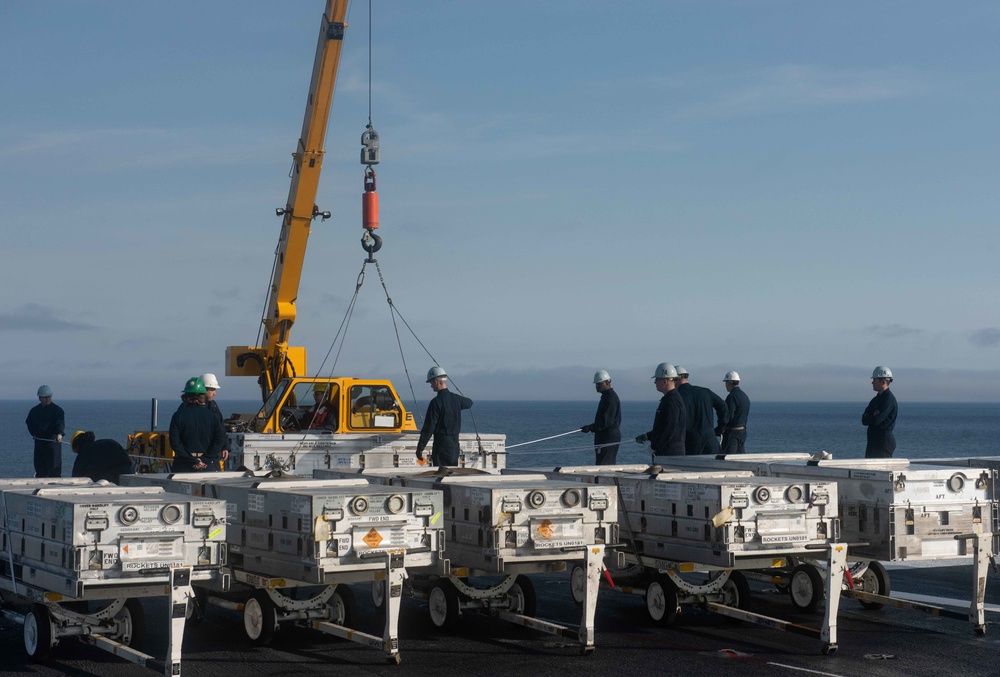 Sailors direct a crane while moving cargo on the flight deck aboard the Nimitz-class aircraft carrier USS John C. Stennis (CVN 74)