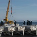 Sailors direct a crane while moving cargo on the flight deck aboard the Nimitz-class aircraft carrier USS John C. Stennis (CVN 74)