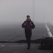 Sailor traverses the flight deck in fog