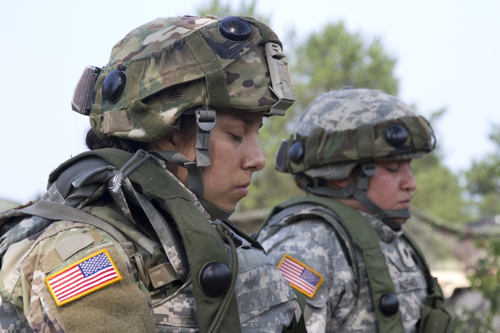 Spc. Mariah Garza (left) and Spc. Alexis Alfaro (right), 422nd Military Police Company, Bakersfield, California, pray during a religious service at Fort McCoy