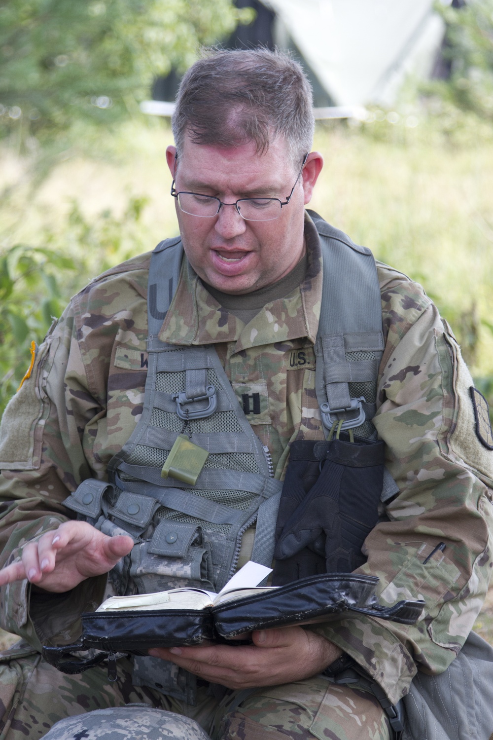 U.S. Army Chaplain (Capt.) Kyle Wiberg, 125th Chaplain Detachment, reads scripture to a group of Soldiers