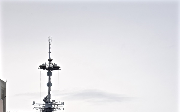 Two gray naval warships are moored side by side at a dock, with a forested hillside visible in the background. The vessel on the right bears the hull number 'F245' on its bow. A Norwegian flag is visible flying from the mast of the left vessel, suggesting a Scandinavian port location.