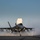 First test bombs dropped from HMS Queen Elizabeth’s F-35 Lightning fighter jets A military stealth fighter jet, consistent with an F-35B variant, is captured on what appears to be the deck of an aircraft carrier or amphibious assault ship. The aircraft has its lift fan door open on top of the fuselage, indicating a short takeoff or vertical landing (STOVL) configuration. Steam or exhaust vapor billows around the landing gear and underside of the aircraft.