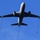 A large military or tanker aircraft is photographed from below against a clear blue sky. The aircraft has three extended refueling drogue hoses with basket-shaped couplings deployed — one from the centerline and one from each wing pod. The aircraft appears to be in a probe-and-drogue aerial refueling configuration, likely a KC-10 or similar tanker variant.