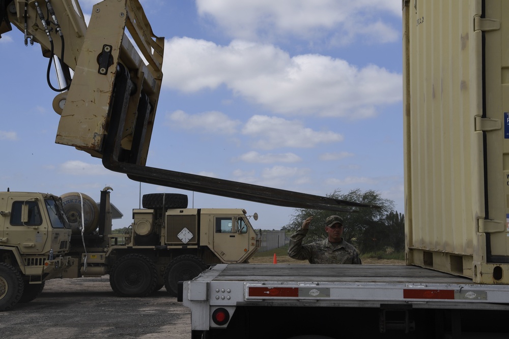 Soldiers remove shipping containers from truck