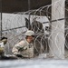 Army Engineers Use Sticks to Push Concertina Wiring Along a Fence