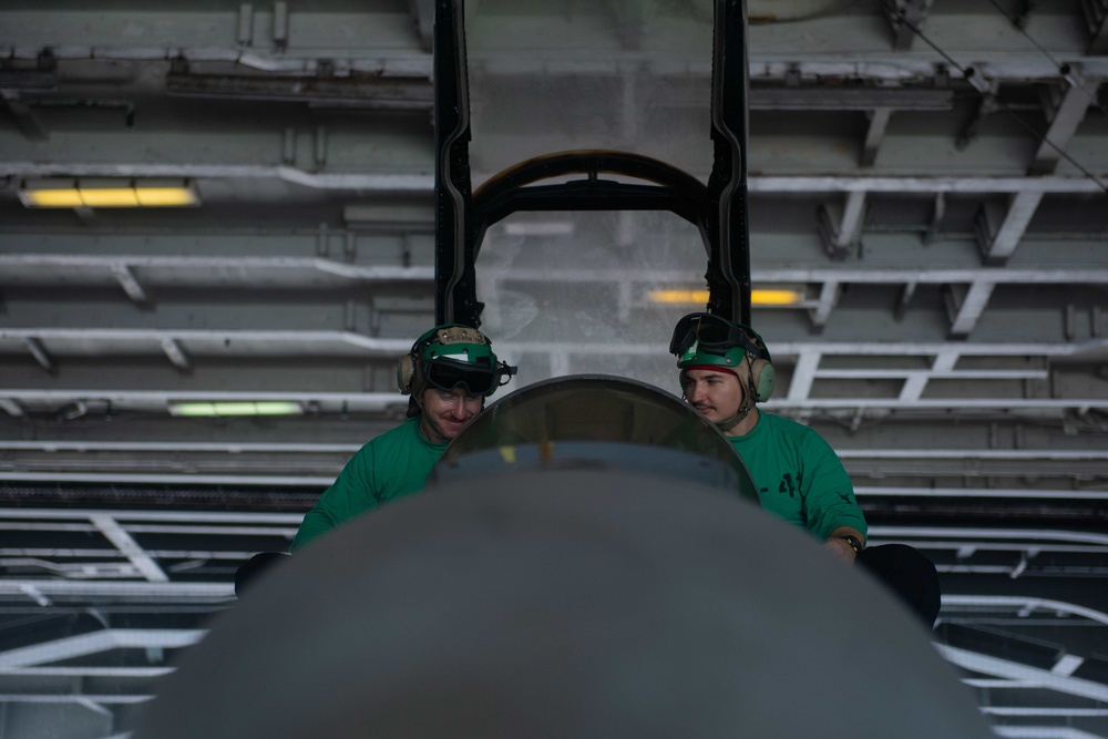 Aviation Electrician’s Mate 3rd Class Daniel Woodard, left, from Farmington, Connecticut, and Aviation Electrician’s Mate 3rd Class Jared Person, from Galt, California, perform maintenance on an F/A-18F Super Hornet.