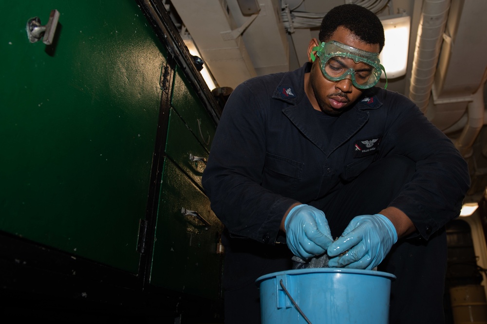 Aviation Support Equipment Technician 2nd Class Willie Mozie, from Alexandria, Louisiana, strips grease from a gear