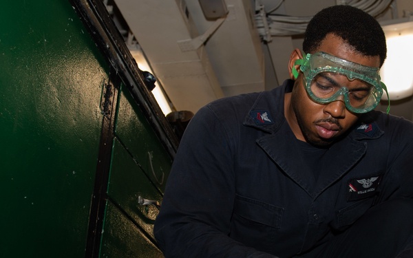 Aviation Support Equipment Technician 2nd Class Willie Mozie, from Alexandria, Louisiana, strips grease from a gear