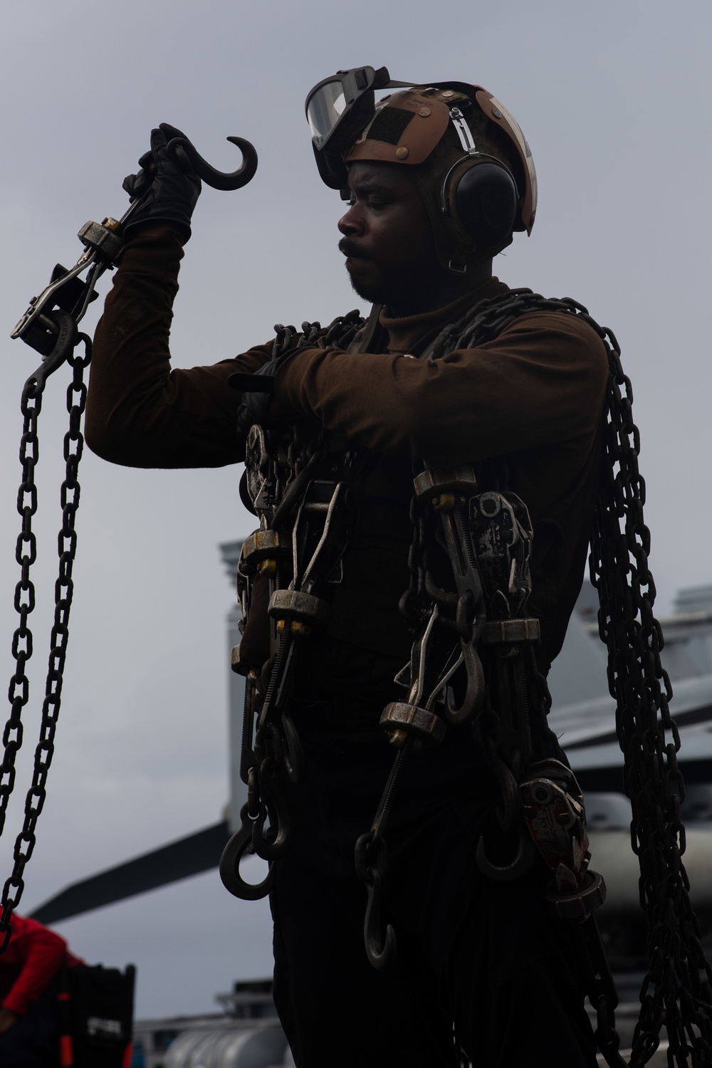 A Sailor gathers chains in preparation to chock and chain an aircraft