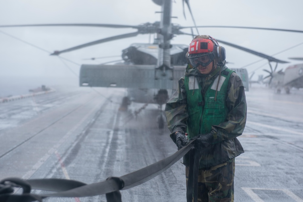 A Sailor removes a strap from an MH-60R Sea Hawk