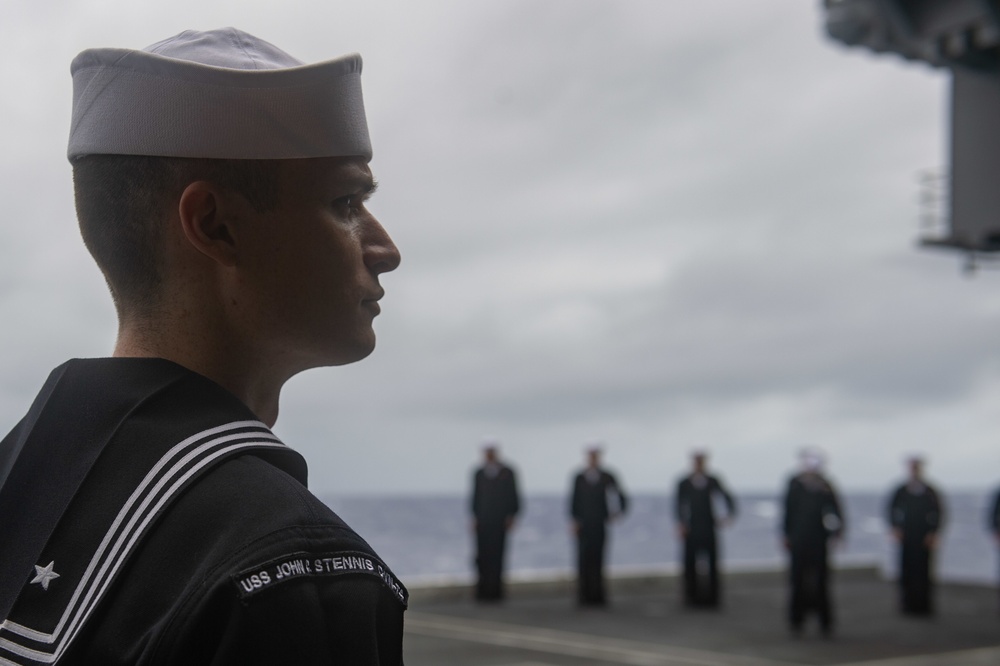 Legalman 1st Class Joshua Boga, from Dayton, Nevada, waits for the call to attention during a burial-at-sea aboard the Nimitz-class aircraft carrier USS John C. Stennis (CVN 74).