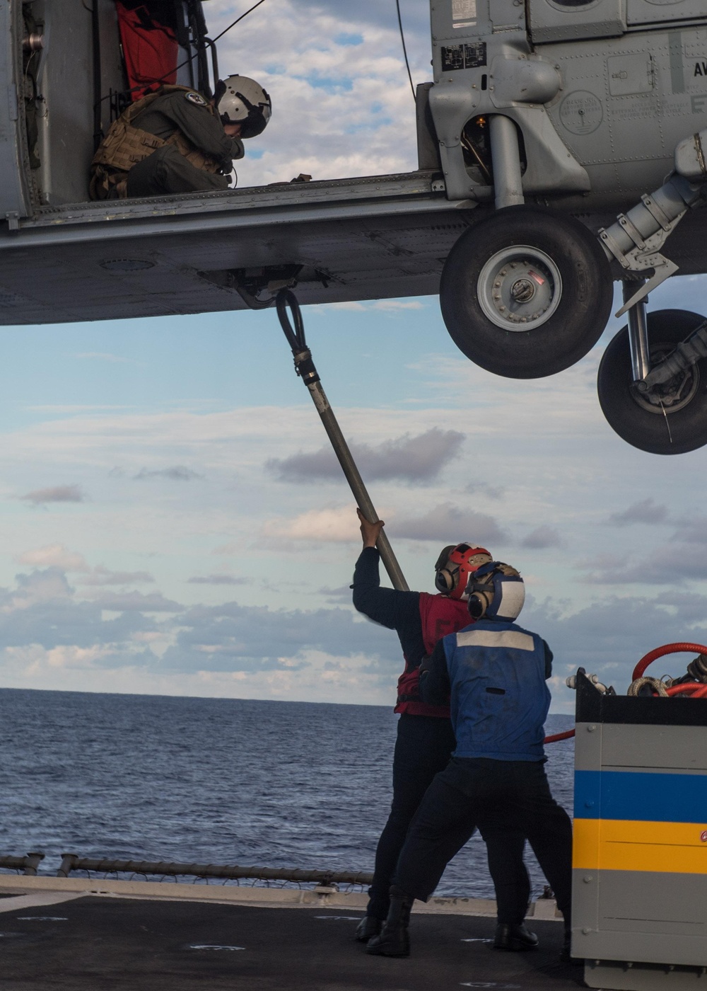 Sailors hook cargo to an MH-60S Sea Hawk, with Helicopter Sea Combat Squadron (HSC) 14, during a vertical replenishment-at-sea.