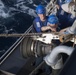 Boatswains Mate 3rd Class Brandon Ross, from Honeapath, South Carolina, observes Seaman Andrew Simpson, from Lafayette, Tennessee, as he cuts stoppers on the span wire at a fuel station aboard USS Spruance (DDG 111) during a replenishment-at-sea.