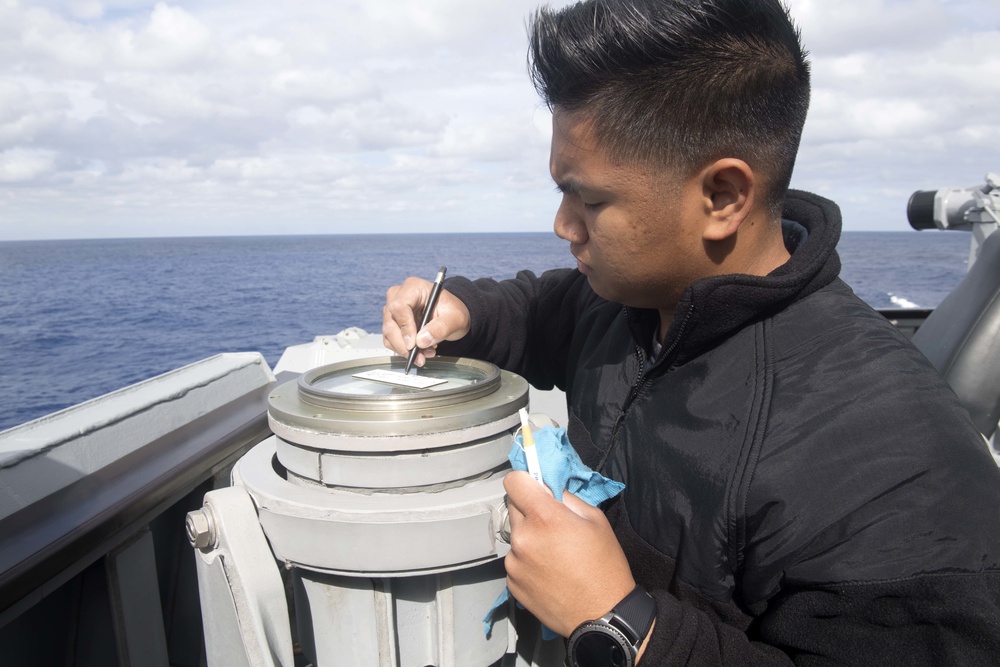 Quartermaster 3rd Class Vhlake Abangan records a gyro error on the compass of a telescopic alidade after shooting an azimuth on the bridge wing of USS Spruance (DDG 111).