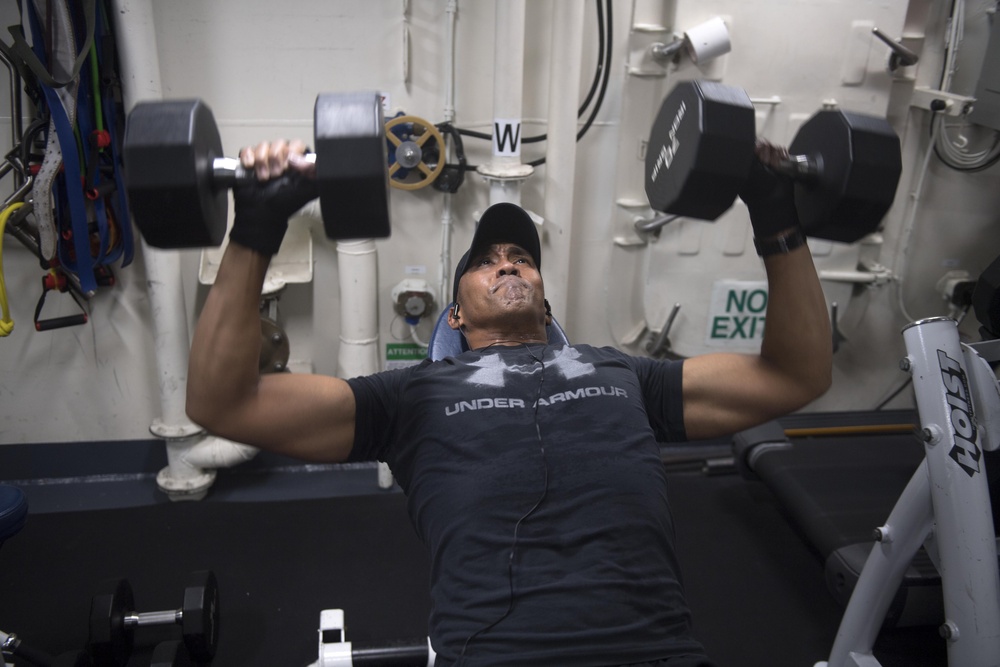 Chief Damage Controlman Marcus White lifts weights in the gym aboard USS Spruance (DDG 111).