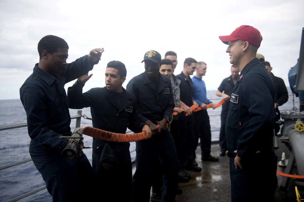 Hull Maintenance Technician 1st Class Brian Canaday, right, watches Operations Specialist Seaman Arturo Ruachomadrigal, second from left, during damage control training aboard USS Spruance (DDG 111).