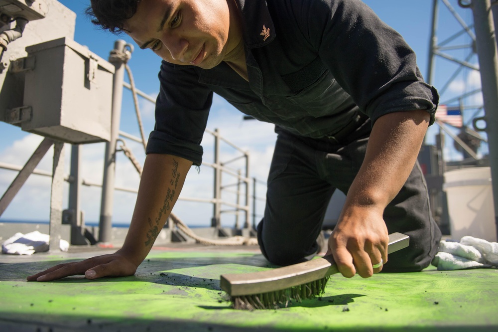 Fire Controlman 2nd Class Deniz Sanchez prepares to repaint a portion of the weather deck aboard USS Mobile Bay (CG 53).