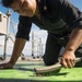 Fire Controlman 2nd Class Deniz Sanchez prepares to repaint a portion of the weather deck aboard USS Mobile Bay (CG 53).