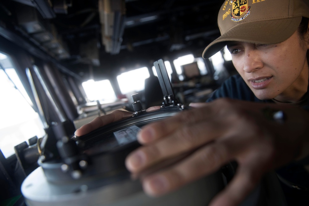 Chief Quartermaster Michele Gosewisch shoots a contact’s bearing as the conning officer in the pilot house aboard USS Spruance (DDG 111).