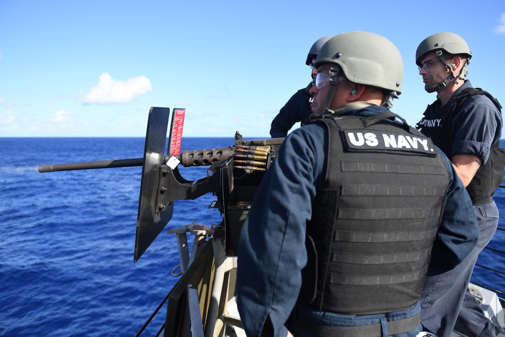 Master-at-Arms 1st Class Derek Bosecker, right, fires a .50-caliber machine gun during a crew-served weapons qualification course aboard USS Spruance (DDG 111).
