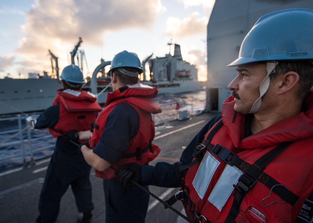 Information Systems Technician 1st Class Rene Acosta handles a communication line during a replenishment-at-sea aboard USS Mobile Bay (CG 53).