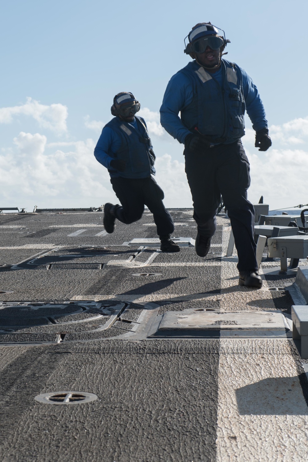 Seaman Davion Gayle, right, and Logistics Specialist 3rd Class Michael Lipscomb return to the foul line after chocking and chaining an MH-60R Sea Hawk aboard USS Chung-Hoon (DDG 93).