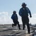 Seaman Davion Gayle, right, and Logistics Specialist 3rd Class Michael Lipscomb return to the foul line after chocking and chaining an MH-60R Sea Hawk aboard USS Chung-Hoon (DDG 93).