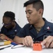 Electricians Mate 2nd Class Michael Deleon, right, and Electricians Mate 3rd Class Sasha Wagner fill out a safety sticker aboard USS Spruance (DDG 111).