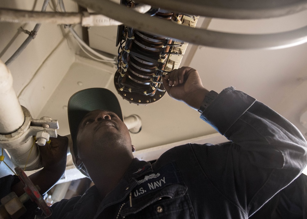 Electrician's Mate 2nd Class Alexander Tramel troubleshoots the recover, assist, secure and traverse system (RAST) aboard USS Mobile Bay (CG 53).