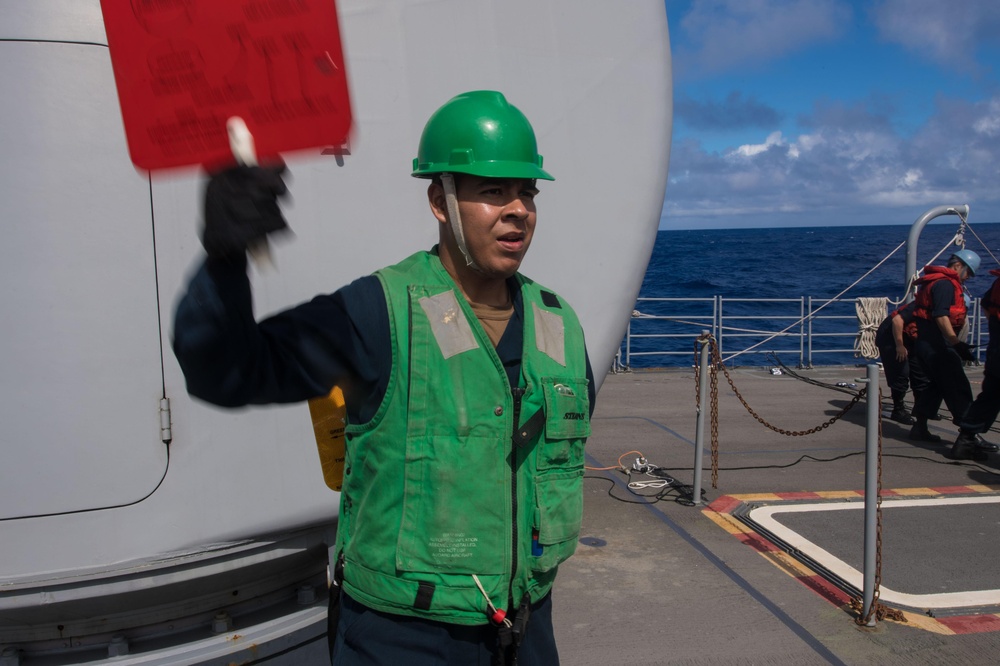 Seaman Anthony Zanbrano, from Fresno, California, signals to USNS Guadalupe (T-AO 200) during a replenishment-at-sea aboard USS Mobile Bay (CG 53).