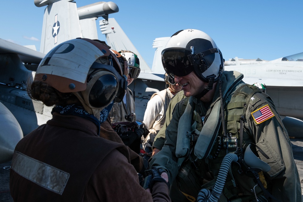Rear Adm. Michael Wettlaufer, commander, Carrier Strike Group (CSG) 3, shakes hands with a Sailor after conducting a pre-flight inspection on an EA-18G Growler on the flight deck aboard the Nimitz-class aircraft carrier USS John C. Stennis (CVN 74).