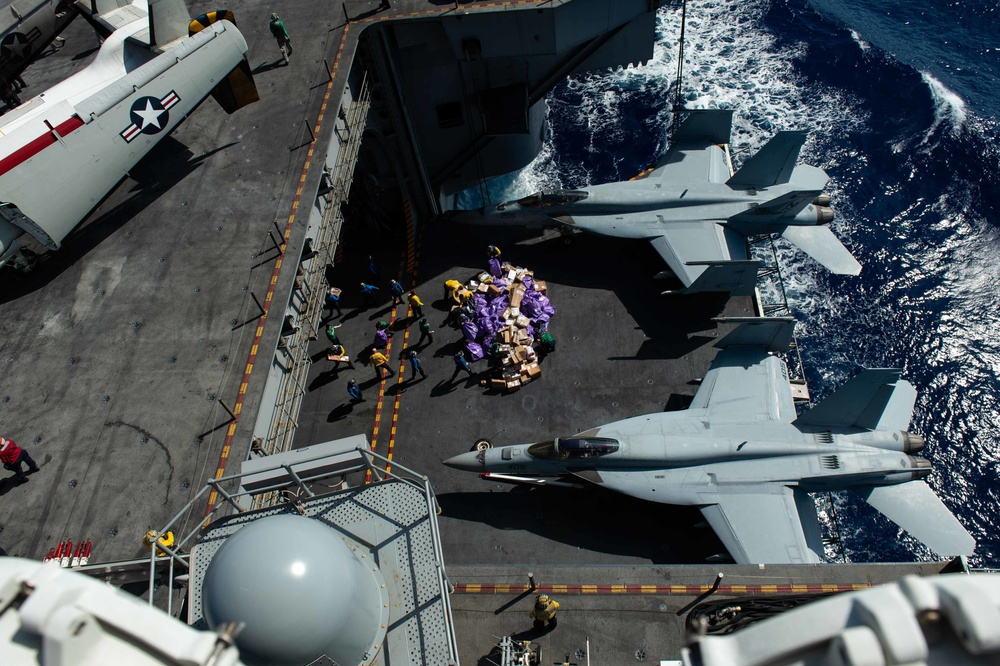 Sailors move mail from an aircraft elevator into the hangar bay during a mail call aboard USS John C. Stennis (CVN 74).