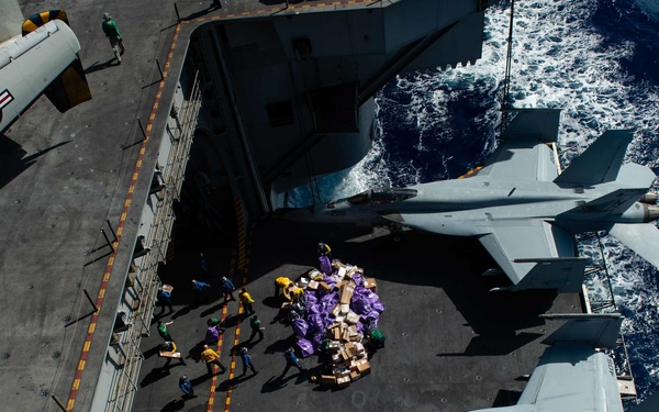 Sailors move mail from an aircraft elevator into the hangar bay during a mail call aboard USS John C. Stennis (CVN 74).