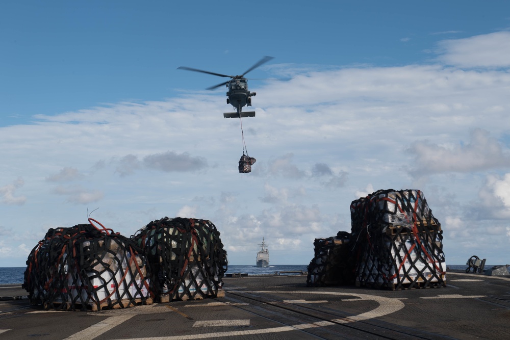 An MH-60R Sea Hawk, with Helicopter Maritime Strike Squadron 37, brings cargo to USS Chung-Hoon (DDG 93), foreground, during a vertical replenishment.