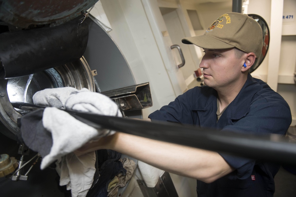 Sonar Technician (Surface) Seaman Kennison Cochran uses rags to dry the cable while retrieving the multifunction towed array (MFTA) aboard USS Spruance (DDG 111).