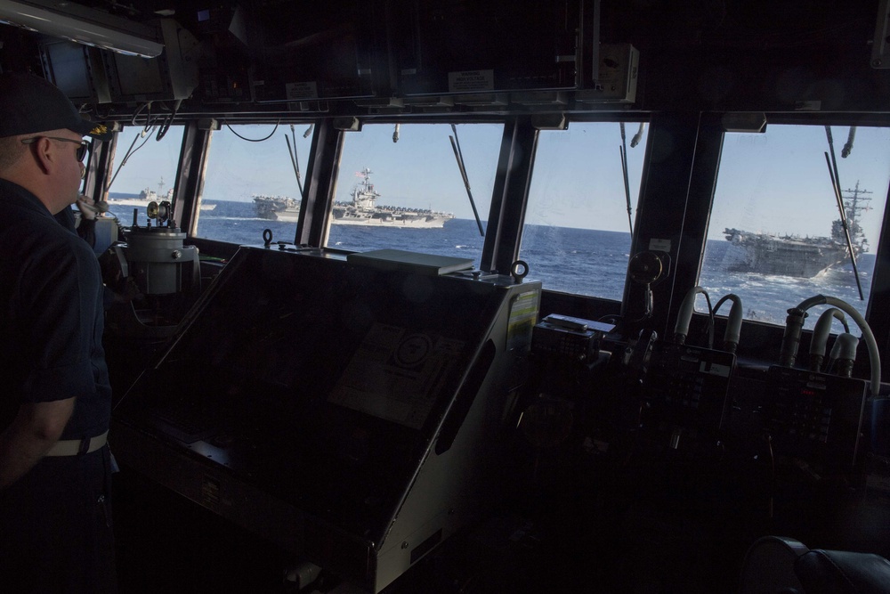 Cmdr. Matthew Smidt, commanding officer of USS Spruance (DDG 111), observes USS Mobile Bay (CG 53), left, USS John C. Stennis (CVN 74) and USS Ronald Reagan (CVN 76).
