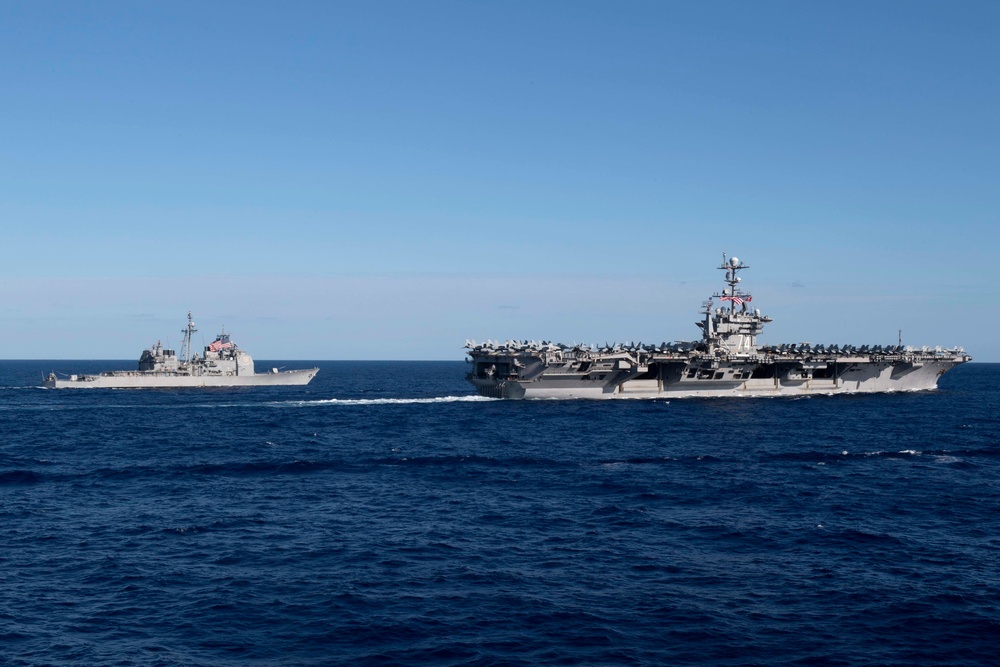 USS Mobile Bay (CG 53) and USS John C. Stennis (CVN 74) cut through the Philippine Sea during formation sailing.