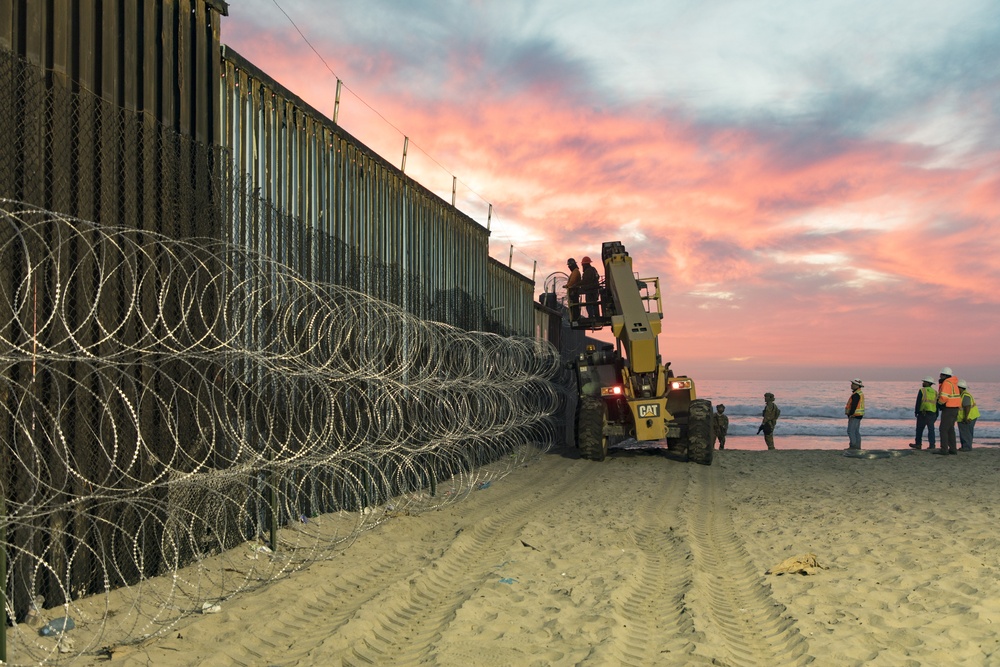 U.S. Border Patrol stands watch during border fence reinforcement