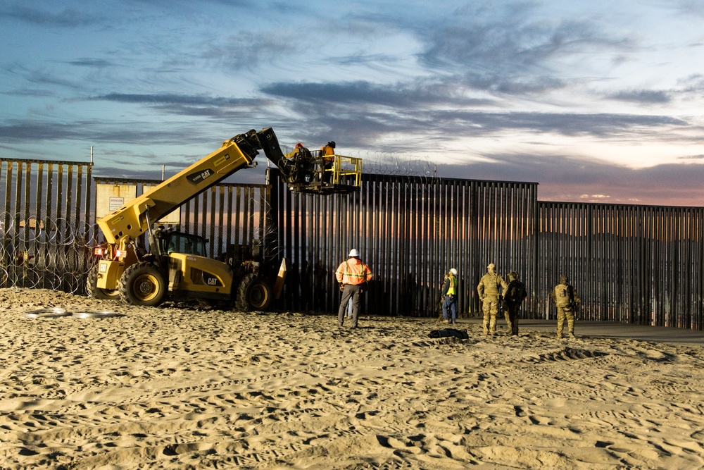 U.S. Border Patrol stands watch during border fence reinforcement