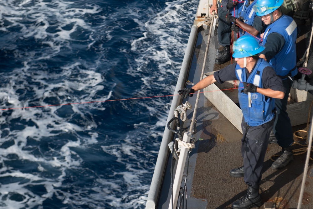 Boatswain’s Mate Seaman Isaiah Rivas hauls in a line at a refueling station aboard USS Chung-Hoon (DDG 93) during a replenishment-at-sea.